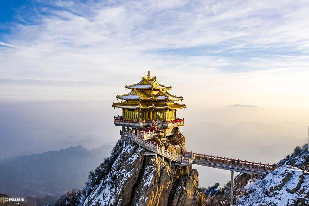 A temple pavilion standing on a snowy mountain ridge under a wide sky